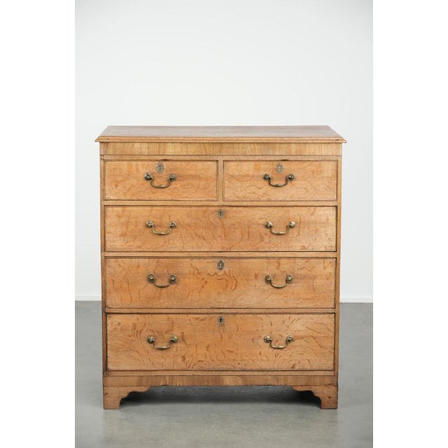 We are offering this large antique English light oak chest of drawers from the 18th century, featuring gold-colored...