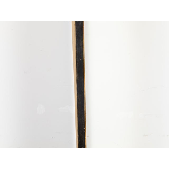 An English painted wall mirror from the mid 20th century, with carved openwork motifs, black and golden tones and...