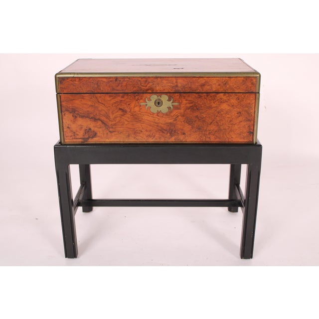 Burled walnut and walnut writing slope with brass mounts, made in 1870, on a late 20th century lacquered stand. The burled...