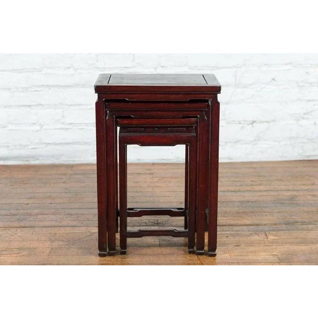 A set of three vintage Chinese rosewood nesting side tables from the mid-20th century with dark reddish brown patina,...