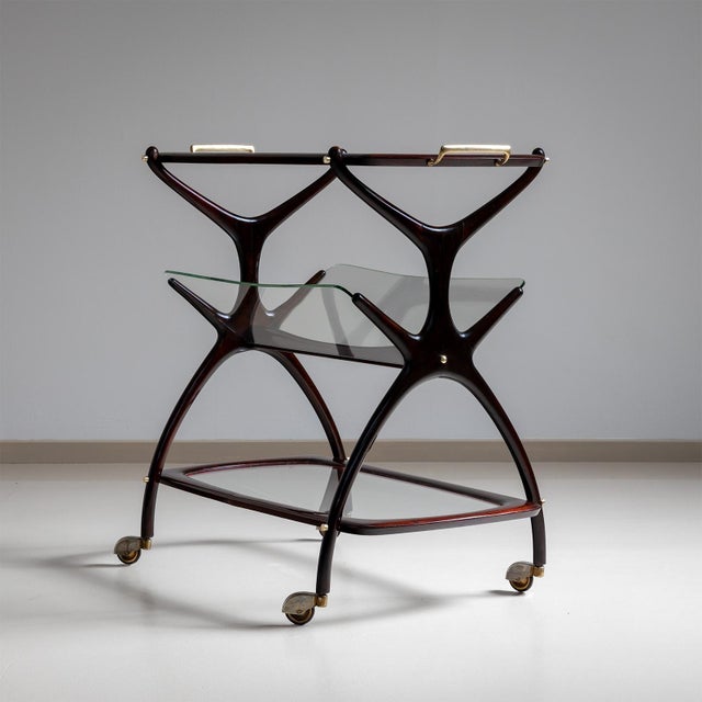 Bar trolley on castors designed by Cesare Lacca. This elegant piece features a top shelf with a glass base and brass...