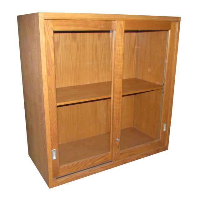 Four foot square wood cabinet with sliding glass doors and one shelf inside. The original hardware is intact, including a...