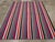 This Mid-20th century Turkish Flatweave Kilim rug, presents a vibrant and rhythmic composition of vertical stripes in...
