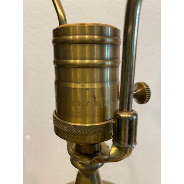 Heavy brass lamp on wooden base with Foo Dog finial. It is marked Rock Mountain, NC