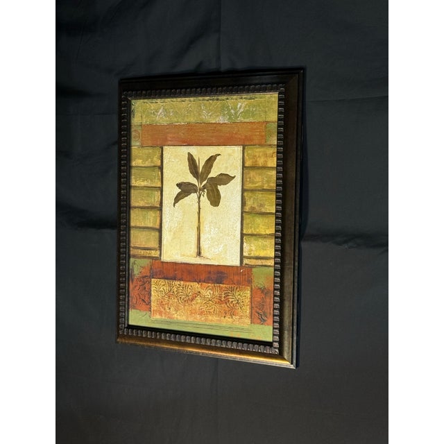 Framed mixed-media style wall art featuring a central banana tree motif on a cream background. The composition uses warm...