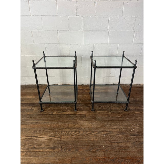 A pair of Italian two-tier iron side tables with clear glass tops. Signed Claudio Rayes. In the style of Giacometti.