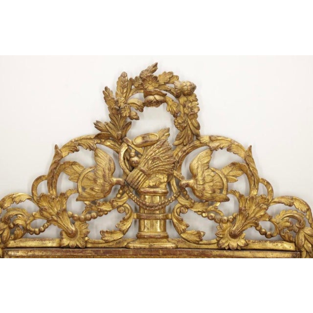 An exceptional and richly ornamented 18th-century Louis XVI carved giltwood mirror, distinguished by its magnificent...