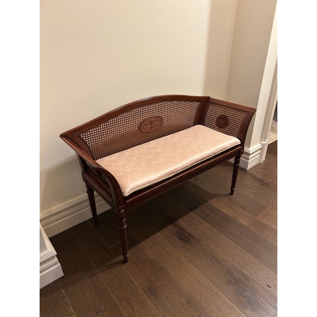 A finely crafted wood bench by Heredia, featuring an elegant silhouette with a gently curved back and integrated arms. The...