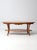 This vintage oak coffee table features curved legs and a carved wheat sheaf apron with an oval top and lower shelf. The...