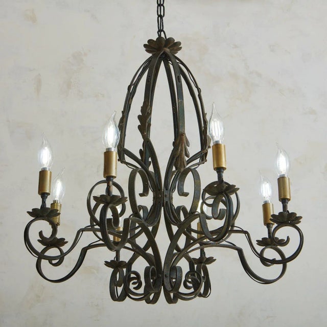 A 1920s French patinated iron chandelier with curved detailing. This chandelier has eight scalloped bobeches and new...