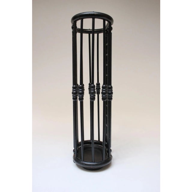 Umbrella stand composed of an ebonized-oak stick and ball constructed frame with painted black cast iron base and brass...