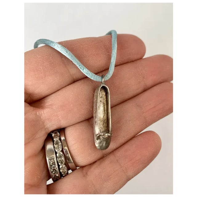 Intricately hand crafted sterling silver (tested) ballet slipper hung on a light blue cord. This necklace is from the 70s...