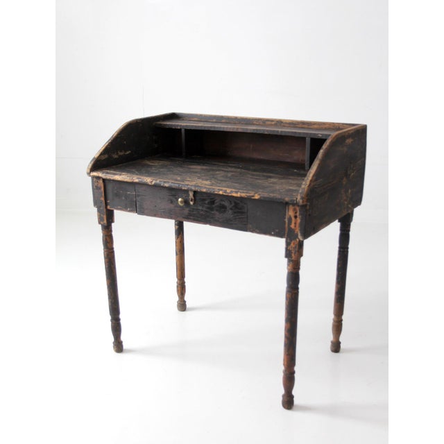 Antique primitive writing desk with raised gallery sides, divided cubbies, a wide center drawer, and slender turned legs....