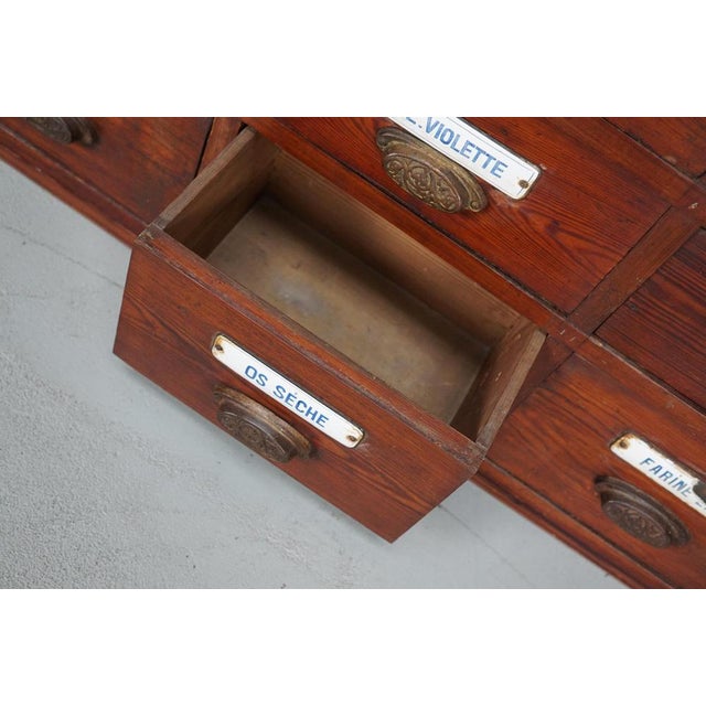 This apothecary bank of drawers was designed and made circa 1900 in Belgium. It was made from pitch pine with cast iron...