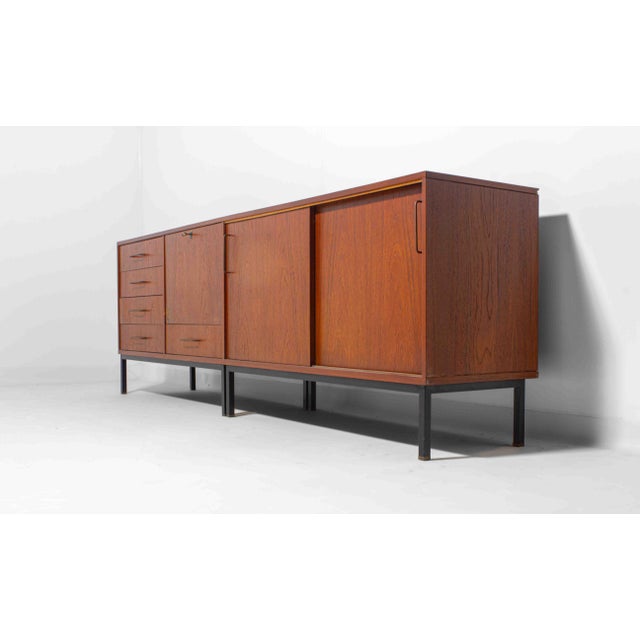 This beautiful sideboard in teak, resting on a sleek black metal base is an amazing example of Belgian modernism during...