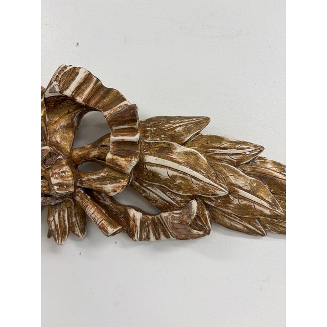 Vintage carved giltwood wall ornament featuring a sculptural central ribbon bow, flowing ribbon swags and symmetrical...