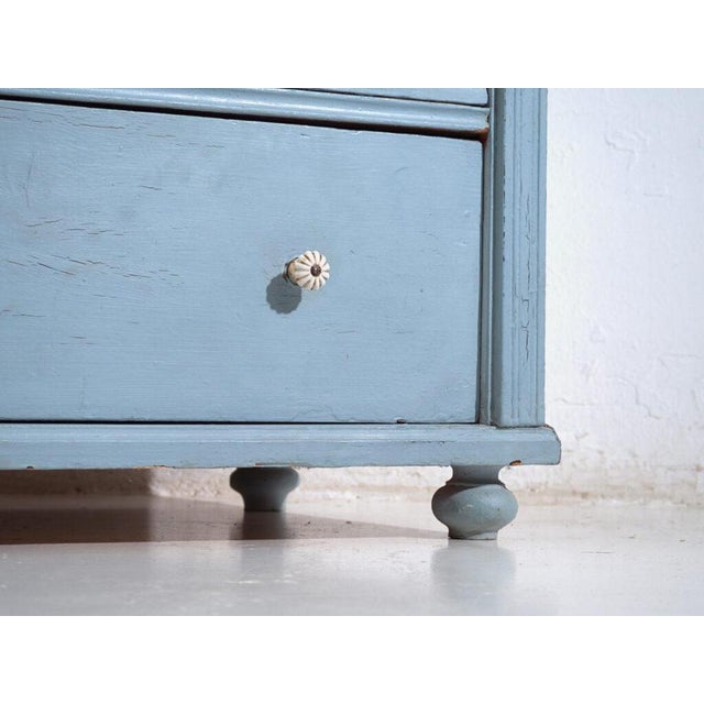 This antique chest of drawers in pine wood is a European storage piece from the early 20th century, originally designed...