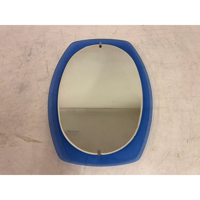 A sculptural Italian wall mirror dating from the 1970s, distinguished by its softly contoured oval form and bold blue...