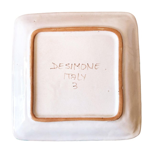 A charming square ceramic plate by celebrated Sicilian ceramicist Giovanni de Simone, hand-painted with a lively street...