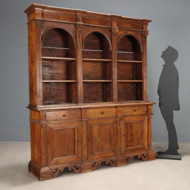 Walnut bookcase constructed from antique woods. The tripartite upper section features open compartments and height-...