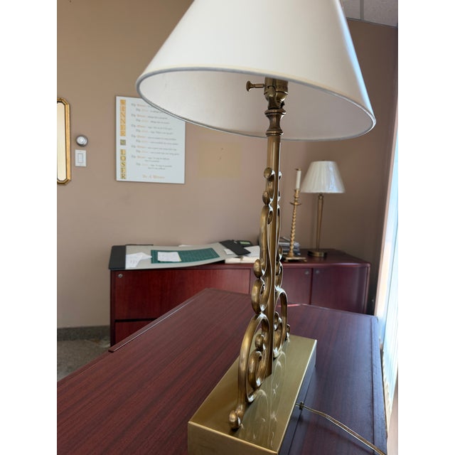 A vintage Haig table lamp featuring an ornate brass base with symmetrical scrollwork and classical detailing. It is...