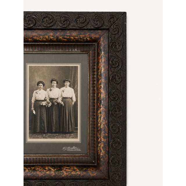 A striking antique carved wood frame housing an original sepia studio photograph, beautifully preserved and rich with late...