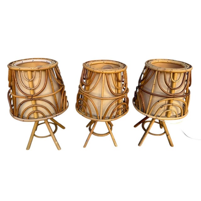 A magnificent set of three mid-century French Riviera-style table lamps, crafted from hand-woven rattan and wicker. These...