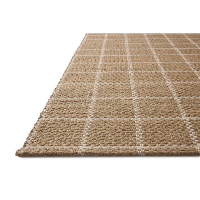 The Fletcher Collection from Chris Loves Julia x Loloi is a handwoven jute rug with a large-scale grid pattern for an...