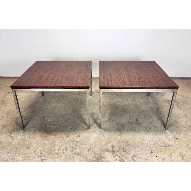 A wonderfully minimalist matched pair of circa 1970’s Florence Knoll side tables with solid chrome legs and walnut pattern...