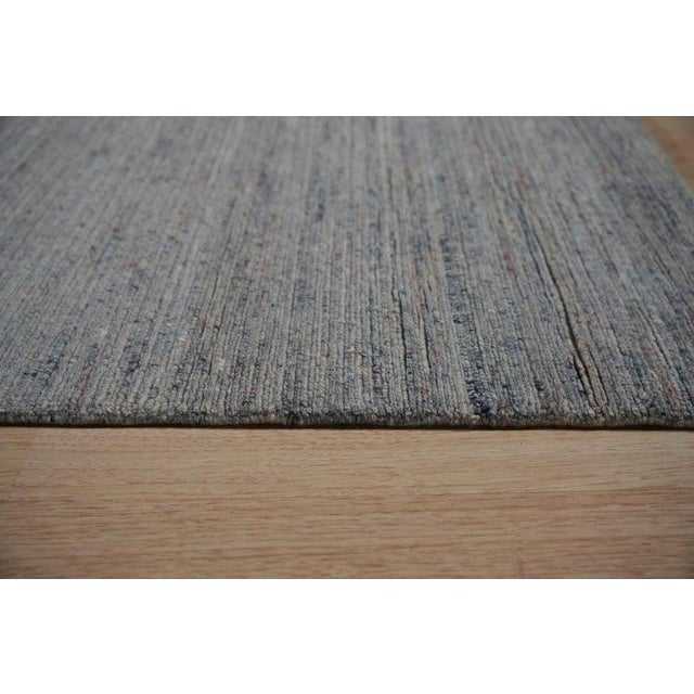 This blue wool rug features a durable hand knotted pile weave construction. Produced in India, it reflects the distinct...
