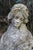 A delightful reconstituted stone figure of a maiden holding flowers or wheat perhaps. She stands bare foot on a circular...