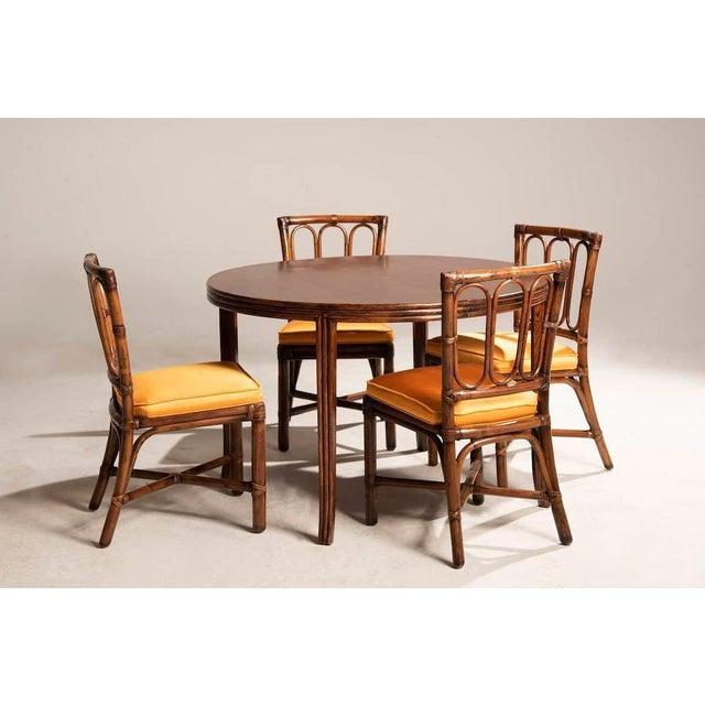 Table in walnut wood by Mc Guire, 113 cm in size, extendable by 45 cm. The extended table has an oval shape, reaching...