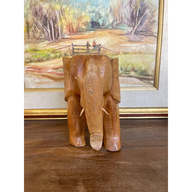 This vintage hand-carved wooden elephant sculpture is crafted from wood, showcasing organic grain patterns and warm...