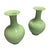 This elegant pair of mid-century modern style porcelain vases showcases a striking monochromatic celadon green glaze with...