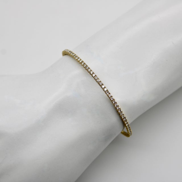 The ingenious design of this 14k gold diamond bangle gives it a snakelike flexibility and allows movement in what presents...