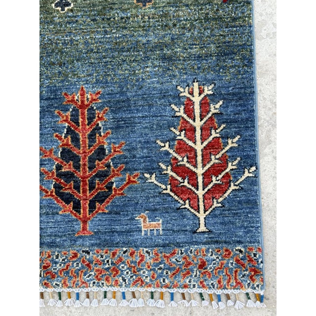 A hand-knotted tribal Gabbeh rug in the Persian Gabbeh tradition, woven in horizontal bands of deep blue and moss green...