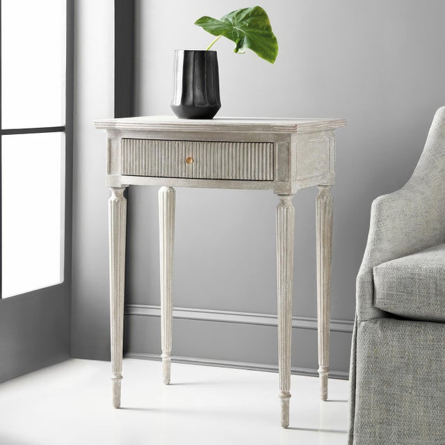 The antique gray finish highlights the table's refined features, including a bow front, a ribbed drawer front and...