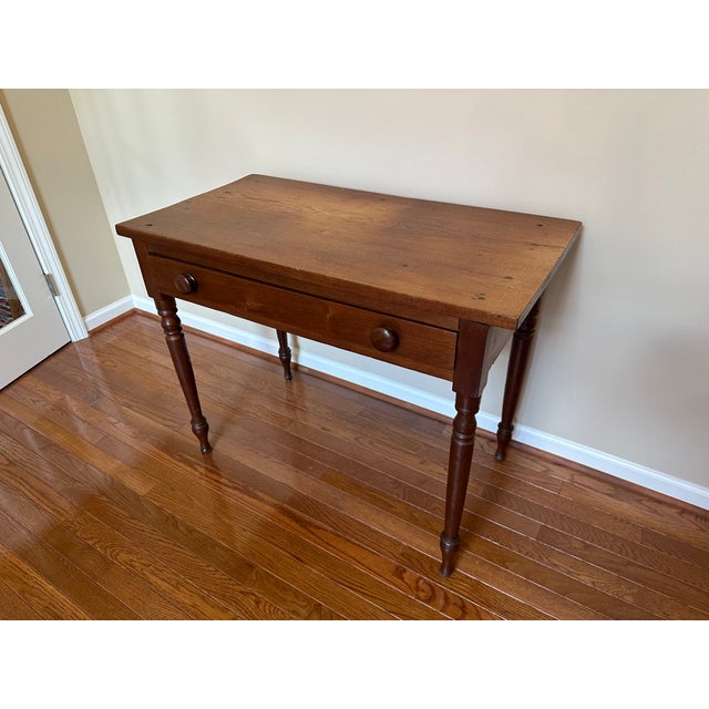 19th Century wood writing table with single drawer and turned legs. The desktop has developed a beautiful patina as it's...