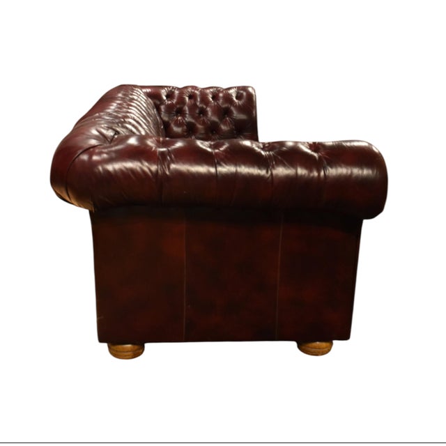 Stylish burgundy or oxblood tufted leather sofa with brass upholstery tacks in the iconic Chesterfield style. This...