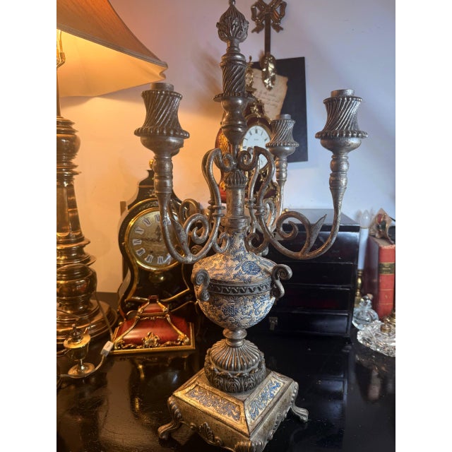 A striking vintage-style candelabra with a dramatic baroque silhouette, sculptural scroll arms, aged metallic finish, and...