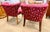 A striking pair of tufted chinoiserie style accent chairs upholstered in a vivid red fabric with gold figural and scenic...