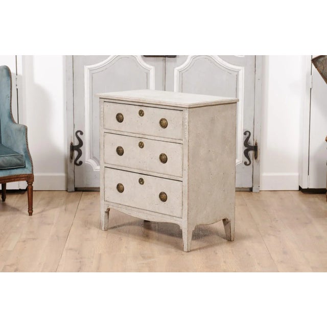 A Swedish Gustavian style light grey painted chest from the 20th century with three drawers, floral carved side posts,...