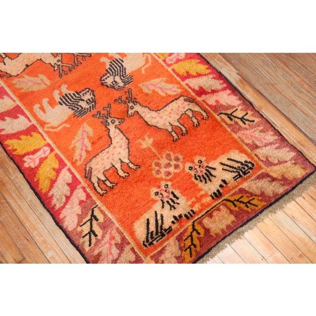 A 2nd quarter of the 20th Century Tibetan Rug featuring an animal pictorial motif on an orange ground color Measures:...