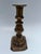 A single antique brass candlestick with rectangular base and pierced cup.