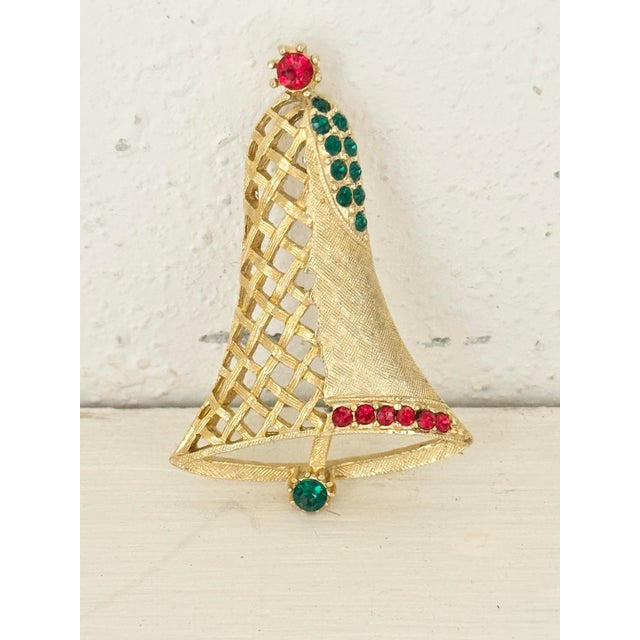 Fun vintage Christmas brooch. Features rhinestones and a holiday bell. Perfect to adorn holiday outfits. This is a pre-...
