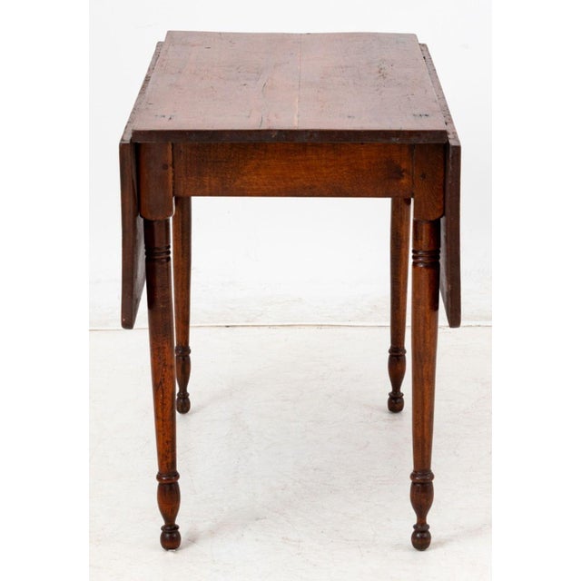Sheraton Style Mahogany Drop Leaf Table, 19th century, with two drop leaves on either side and four turned tapered legs....