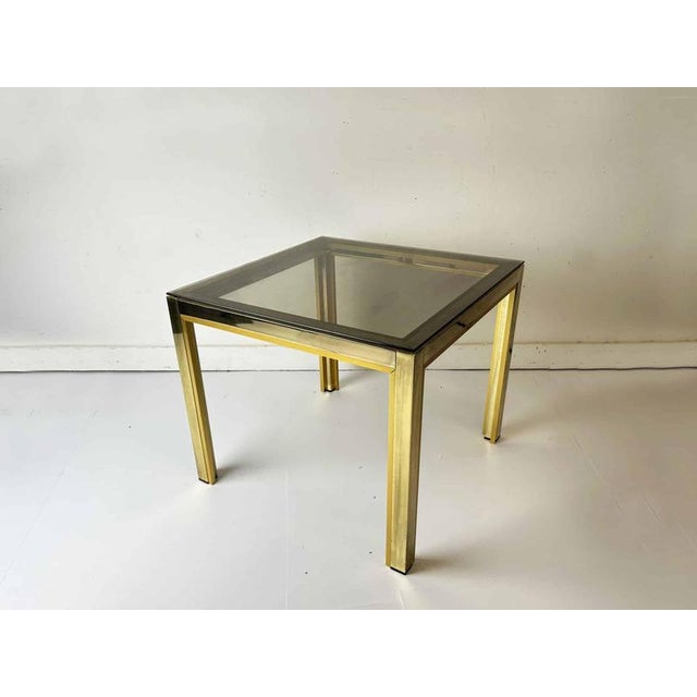 A 1970s Italian-style side table in the Hollywood Regency manner. The square frame combines two tones of brass finish:...