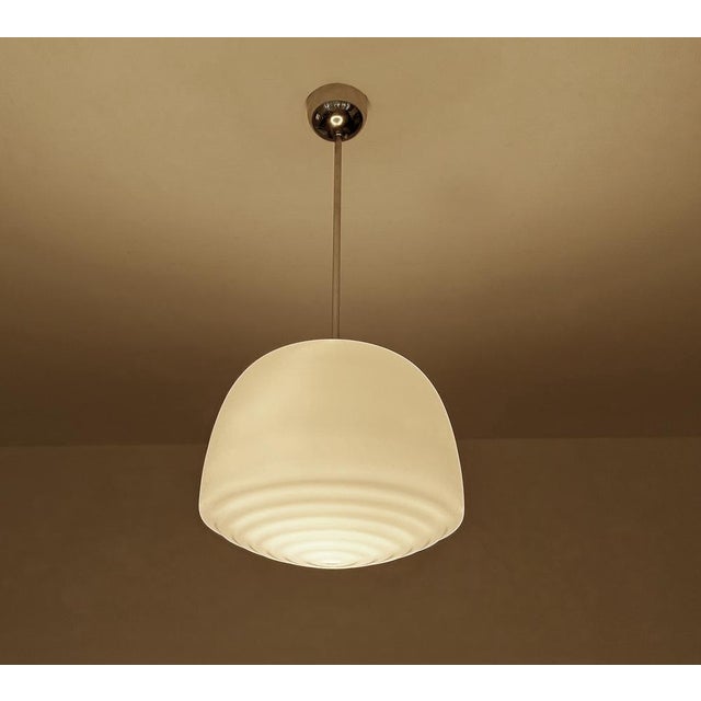 Art Deco bauhaus pendant light, featuring a pear shaped opaline glass shade with a ripple bottom pattern mounted on a...