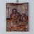 The wooden carved relief shows a grandfather with grandson on his lap. The granddaughter is sitting on the chair and hides...