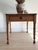 A square-cornered pine table on ring-turned legs, with a single working drawer closing on a dark turned knob. The top has...